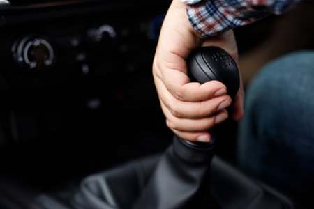 Male hand holding manual gearbox in car