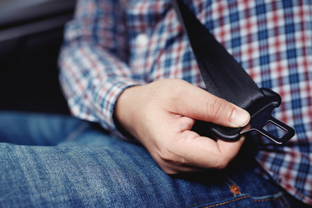 Men's hand fastens the seat belt of the car.