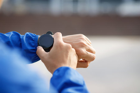Running athlete man looking at smartwatch heart rate monitor GPS smart watch.