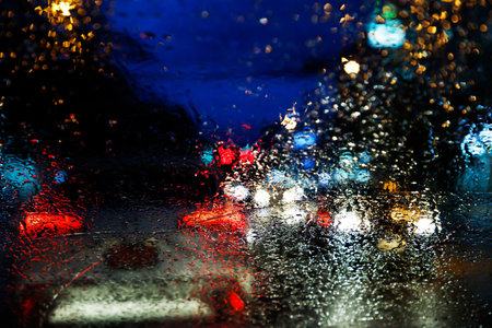 Drops Of Rain Drizzle on the glass windshield in the night. street in the heavy rain. Bokeh Tail light. soft Focus. Please drive carefully, slippery road. soft focus. traffic jam car.の写真素材