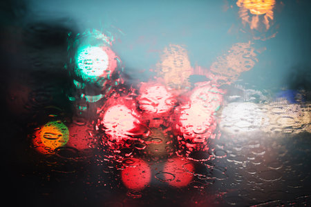Drops Of Rain Drizzle on the glass windshield in the night. street in the heavy rain. Bokeh Tail light. soft Focus. Please drive carefully, slippery road. soft focus. traffic jam car.の写真素材