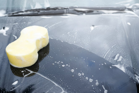 yellow sponge and soap over the car for washing. Motor hood being cleaned. Concept car wash clean. Leave space for writing messages.の写真素材