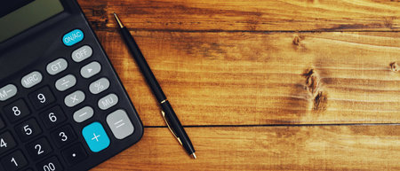 accountant's calculator with a black pen on a wooden tableの写真素材