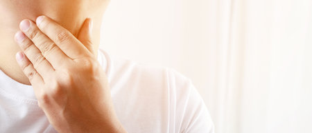 sore throat pain. Closeup of young man sick holding her inflamed throat using hands to touch the ill...