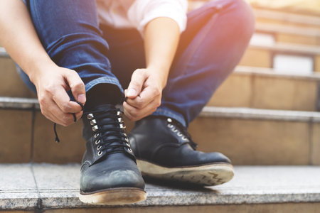 Close up of young man tying shoelaces on his sneakers.の写真素材
