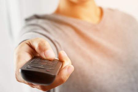 Woman presses online TV remote at home