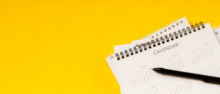 calendar month schedule to make appointment meeting or manage timetable each day lay and pen on yellow background for planning work and travel concept.の写真素材