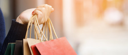 Close up of consumerism young woman holding hand many shopping bag in fashion boutique after buying presents while walking along the street with copy space , enjoying summer sale and people conceptの写真素材