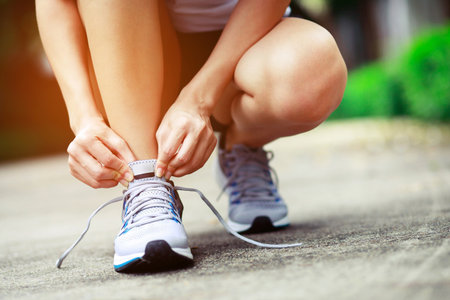 Running shoes. close up female athlete tying laces for jogging on road. Runner ties getting ready...