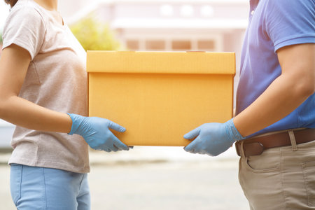 parcel delivery man of a package through a service. and close up hand customer female accepting a delivery of boxes from delivery man postal send direct to home.の写真素材