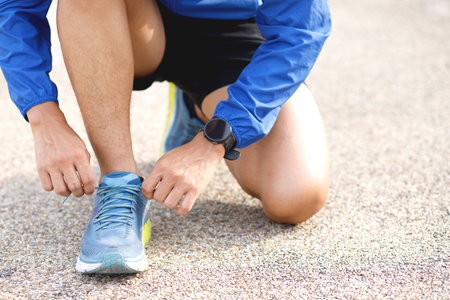 Running shoes. Barefoot running shoes close up. male athlete sitting tying laces for jogging on road. Runner ties getting ready for training. Sport lifestyle. Sunny in the morning.の写真素材