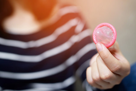 Condom ready to use in female hand, give safe sex concept on the bed Prevent infection and Contraceptives control the birth rate or safe prophylactic. World AIDS Day,の写真素材