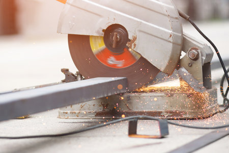 A worker cutting steel with a steel cutting machine sparked at a construction site.