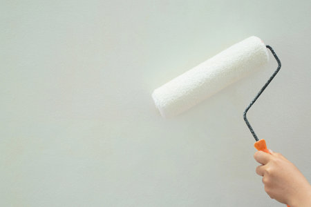 Roller Brush Painting, Worker painting on surface wall  Painting apartment, renovating with white color  paint. Leave empty copy space white to write descriptive text beside.の写真素材