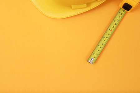 The yellow measuring tape for the mason is placed on a yellow background. Soft focus.