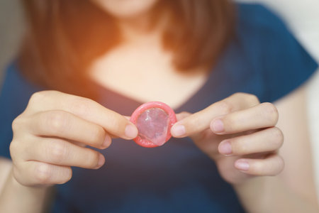 Condom ready to use in female hand, give safe sex concept on the bed Prevent infection and Contraceptives control the birth rate or safe prophylactic. World AIDS Day,の写真素材