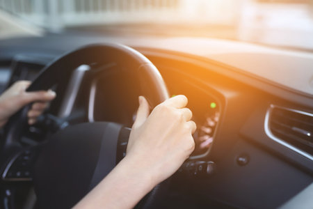 Close up of hands hold steering wheel young woman driving a car riding on the road. driver trip of travel.の写真素材