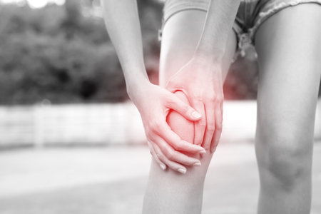 female touching painful twisted or broken ankle. Athlete training accident. Sport sprain cause injury knee leg bones while run in outdoor the park.の写真素材
