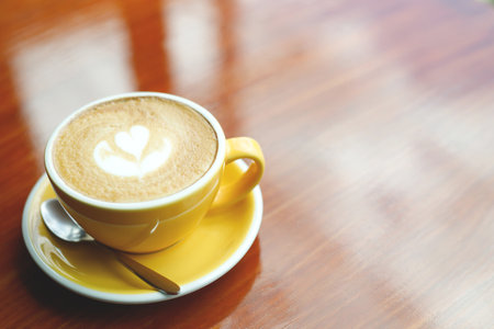 hot coffee cup latte art with spoon Serve ready to drink in cafe on wooden table coffee shop.  Leave copy space empty to write the side text. soft focus.の写真素材