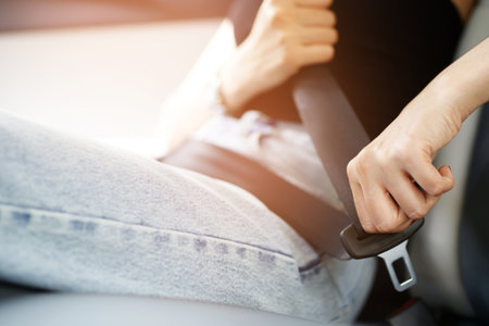 Close Up of people business woman hand fastening seat safety belt in car for safety before driving on the road. concept transport travel. soft focus.の写真素材