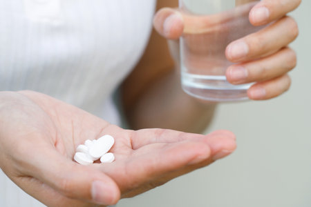 close up hand woman taking pill take a medicine in hand holding a cup glass of drinking water. Stop drug use Taking Medication health care medical concept.の写真素材
