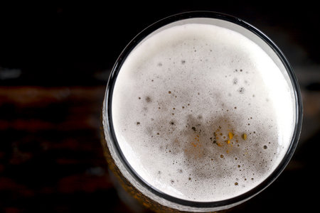 Cold beer with foam in a glass, ready to drink.