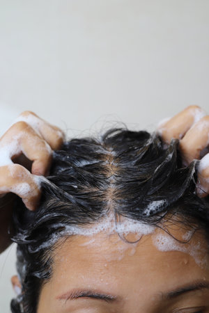 A woman is taking a shower and washing her hair in the bathroom.の写真素材