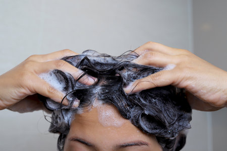 A woman is taking a shower and washing her hair in the bathroom.の写真素材