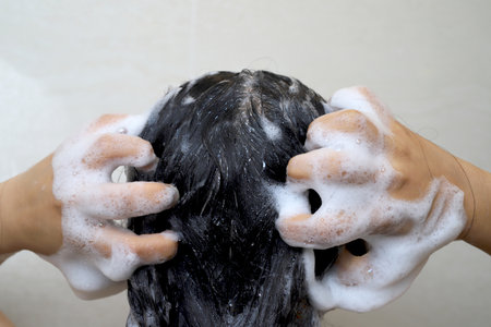 A woman is taking a shower and washing her hair in the bathroom.の写真素材