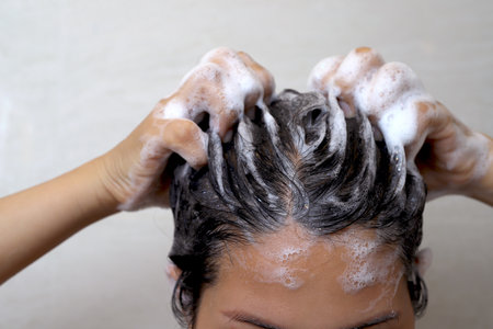 A woman is taking a shower and washing her hair in the bathroom.の写真素材