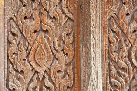 old wooden carving in Thai style on the door of Buddhist churchの写真素材