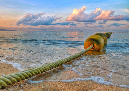 Line of buoy on the sea. Jomtien Beach in the morning with beautiful sunrise and cloudy blue sky.の素材