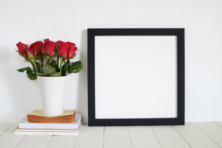 square frame with red roses on wooden tableの写真素材