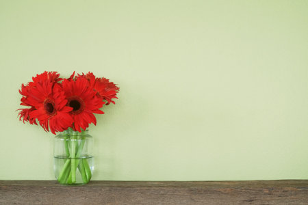 red flower in glass bottle on wooden shelf with copy spaceの写真素材