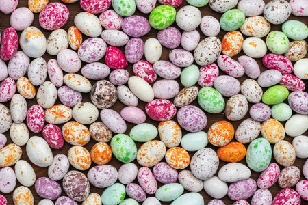 Mix of sweets in the form of multi-colored spotted pebbles on a brown wooden background. A high resolution.の写真素材