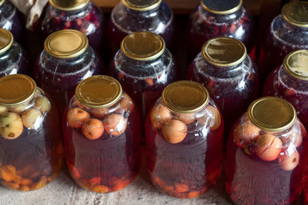 Natural home-made fruit drink. Glass jars with a compote of pink apples. Drink storage. Blurred background. View from above.の写真素材