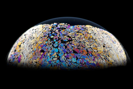 Half a soap bubble on a black background. Beautiful patterns. Macro photo.