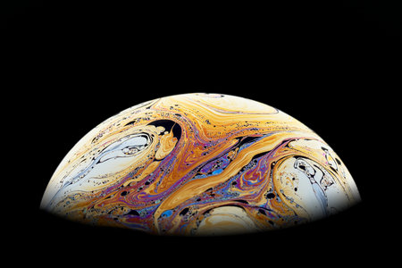 Half a soap bubble. Bright, beautiful patterns. Isolated on black background. Close-up.の写真素材