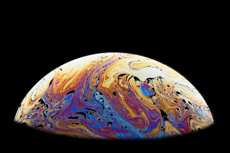 Half a soap bubble. Fantastically vibrant color patterns. Isolated on black background. Close-up.の写真素材
