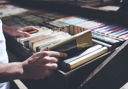 Male hand taking out a book from a horizontal bookshelf of woodenの写真素材