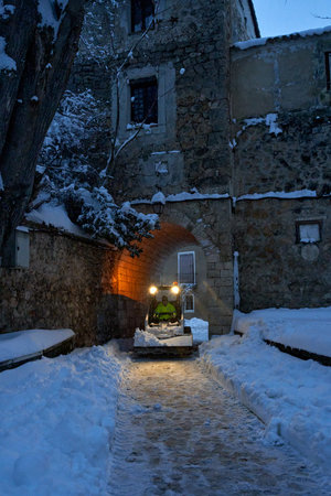 Brihuega, Spain - January 9, 2021: An excavator transports salt to remove fallen snow after the Filomena snow storm in the town of Brihuega (Spain).のeditorial素材