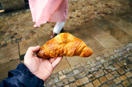 Hand holding a classic French croissant with a delicious golden crustの写真素材