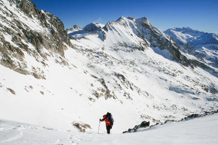 Snow hiker walking on snow with the view of the mountains and blue sky in the background in Ordesa Natural Park, Pyrenees Spainの写真素材