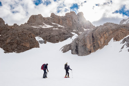 Snow hikers walking on a snowy hillside on a sunny day in Picos de Europa mountains, Spainの写真素材
