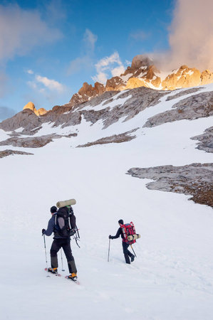 Snows hiker walking on a snowy hillside on a sunny day in Picos de Europa mountains, Spainの写真素材