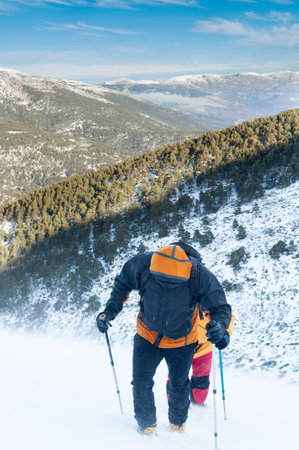 Two snow hikers climbing a snowy mountain during a snowstorm in Cabezas de Hierro mountain in Spainの写真素材