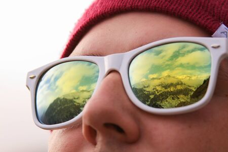 Mountains reflected in sunglasses of the traveler. Active person looking at mountains in winter. Image can be used for winter sport, outside in nature.の写真素材