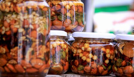 Various types of nuts in honey jars. Honey is a sweet, viscous food substance made by honey bees and...
