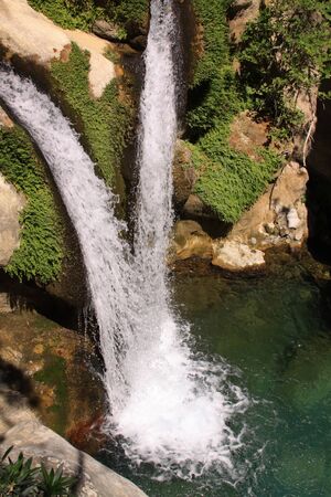 Two waterfalls meet as they flow downstream in a clean pond in natural canyonの写真素材
