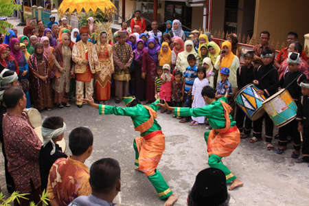 Traditional Silat dance at Minangkabau wedding, in Padang, West Sumatra, Indonesia. Village people dressed in festive clothes, dancers and music orchestra, attending public ceremony in the street.のeditorial素材